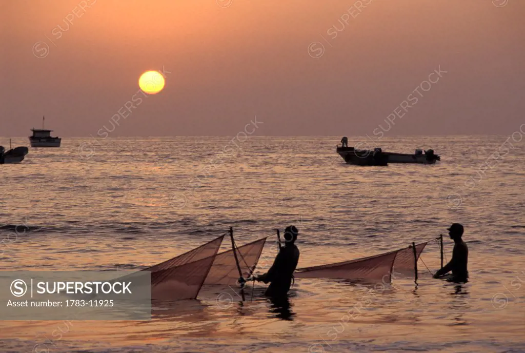 Fishermen holding nets in sea at sunset, Puerto Lopez, Ecuador.