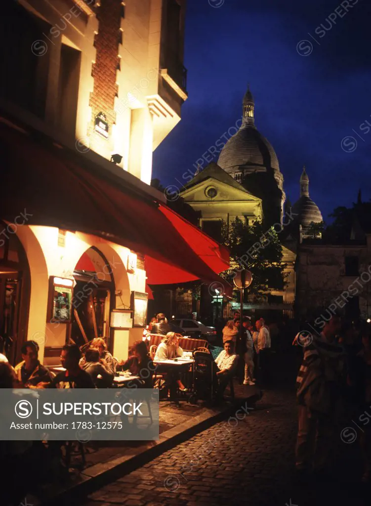Cafes at dusk, Sacre-Coeur church, Paris, France.