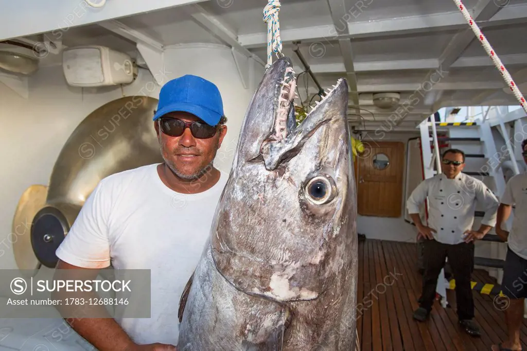 A fisherman poses with a dogtooth tuna (Gymnosarda unicolor); Tahiti