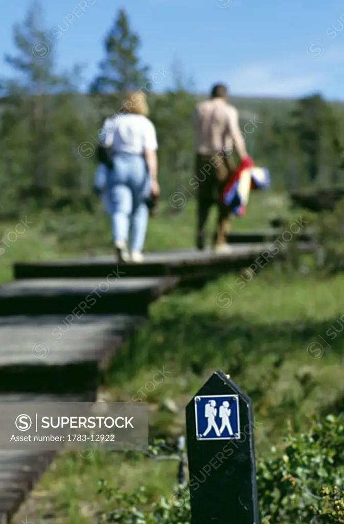 Couple walking on wooden path, Finland