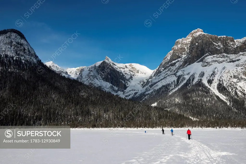 Walking and skiing in the snow on frozen Lake Louise; Lake Louise, Alberta, Canada