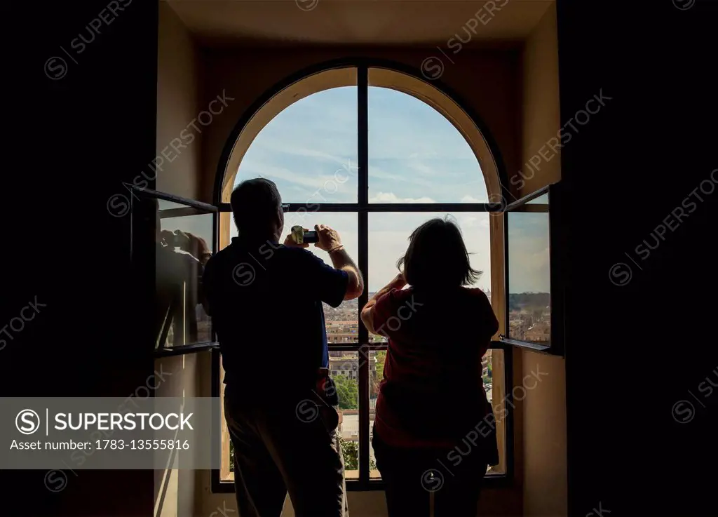 Tourists taking photographs from a window inside The Vatican; Rome, Italy