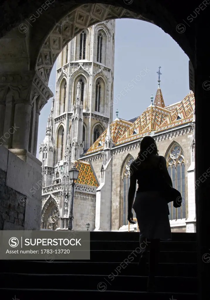 Woman walking up stairs towards church, Varhegy District, also known as the Castle District, in Budapest, Hungary