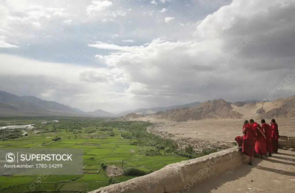  Buddhist monks on rooftop at Thikse Monastery looking over Indus Valley, Gompa , near Leh , Ladakh , India