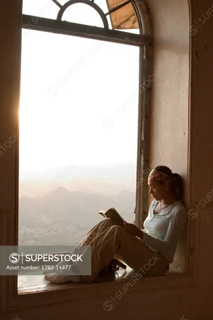 Female traveller reading in window, Udaipur, India