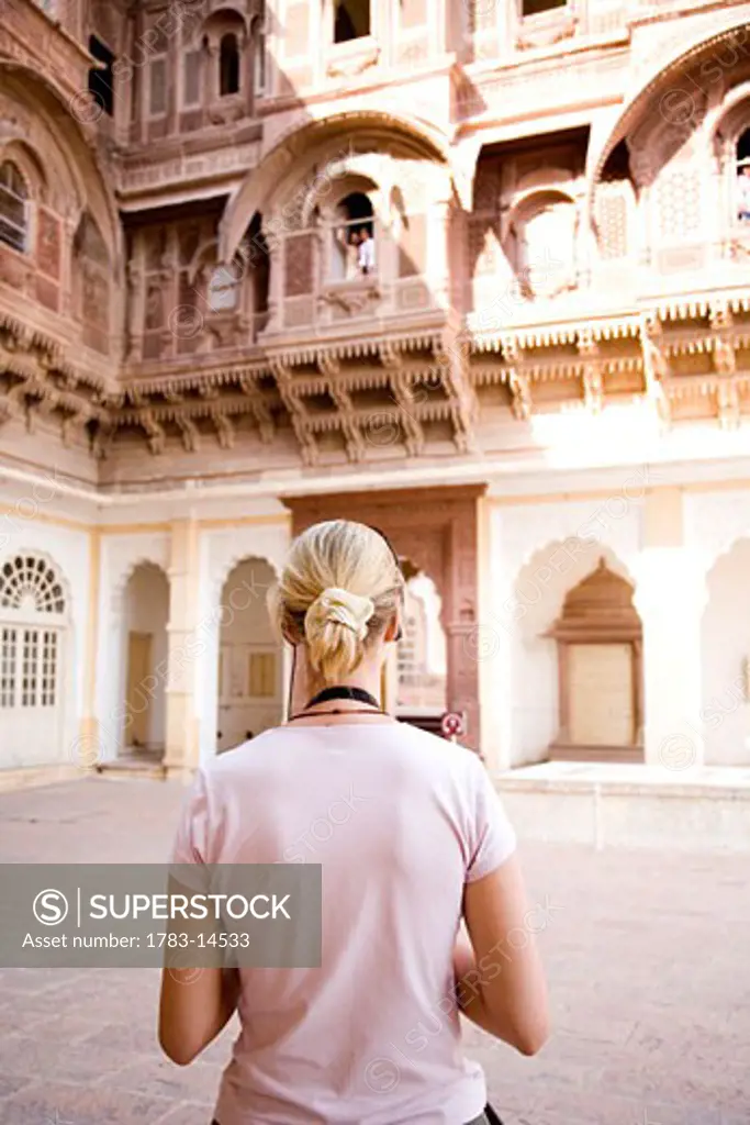 Blond tourist looking at building in Fort Mehrangarh, Jodpur, Rajasthan, India