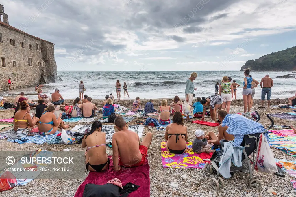 Tourists in bathing suits on the beach on the Bay of Kotor; Budva, Budva Municipality, Montenegro