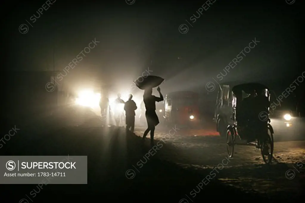 Silhouettes of traffic and people carrying sacks on their heads at night, Agartala , Tripura , North East States , India