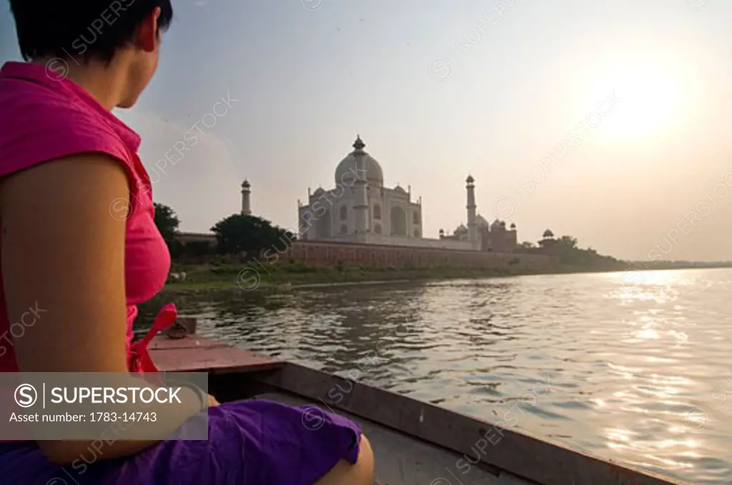 Tourist on boat crossing the Yamuna River at dusk by the Taj Mahal, Agra, Uttar Pradesh, India