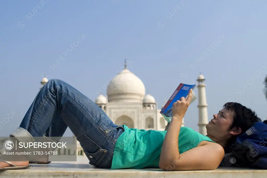 Woman reading guide book in front of the Taj Mahal, Side View, Agra, Uttar Pradesh, India