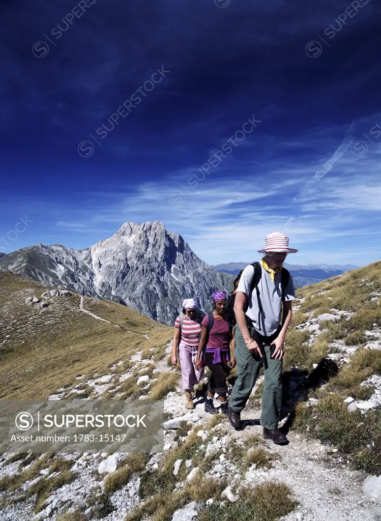 Three women walking along ridge in front of Corno Grande in the Campo Imperatore, Parco Nationale del Gran Sasso, Abruzzo, Italy