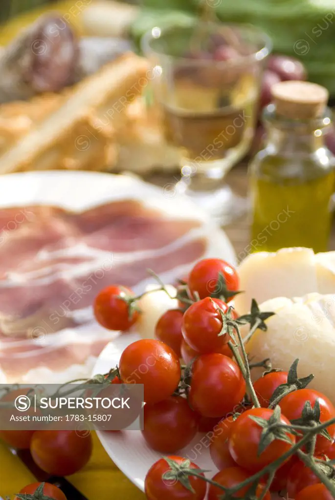 Prosciutto ham, cheese, tomatoes, white wine and, bread and olive oil , close up, Tuscany, Italy