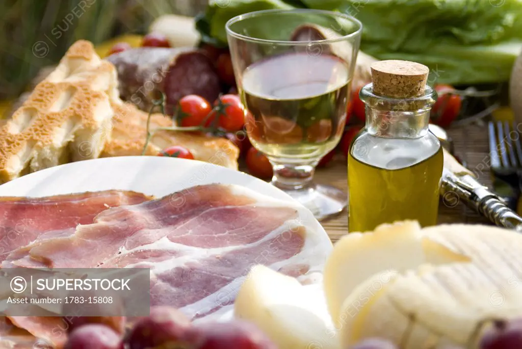Prosciutto ham, cheese, tomatoes, white wine, bread and olive oil, close up, Tuscany, Italy