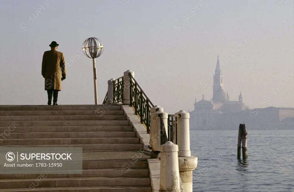 Man going up stairs on the side of the lagoon, Venice, Italy