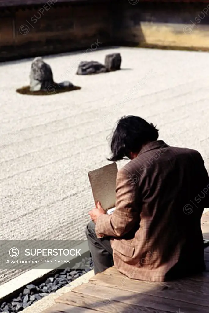 Man drawing in Abbot's Garden of Ryoanji , Kyoto, Japan.  The famous abstract rock Zen Gardens at Ryoanji were created by 16th century artist Soami. 