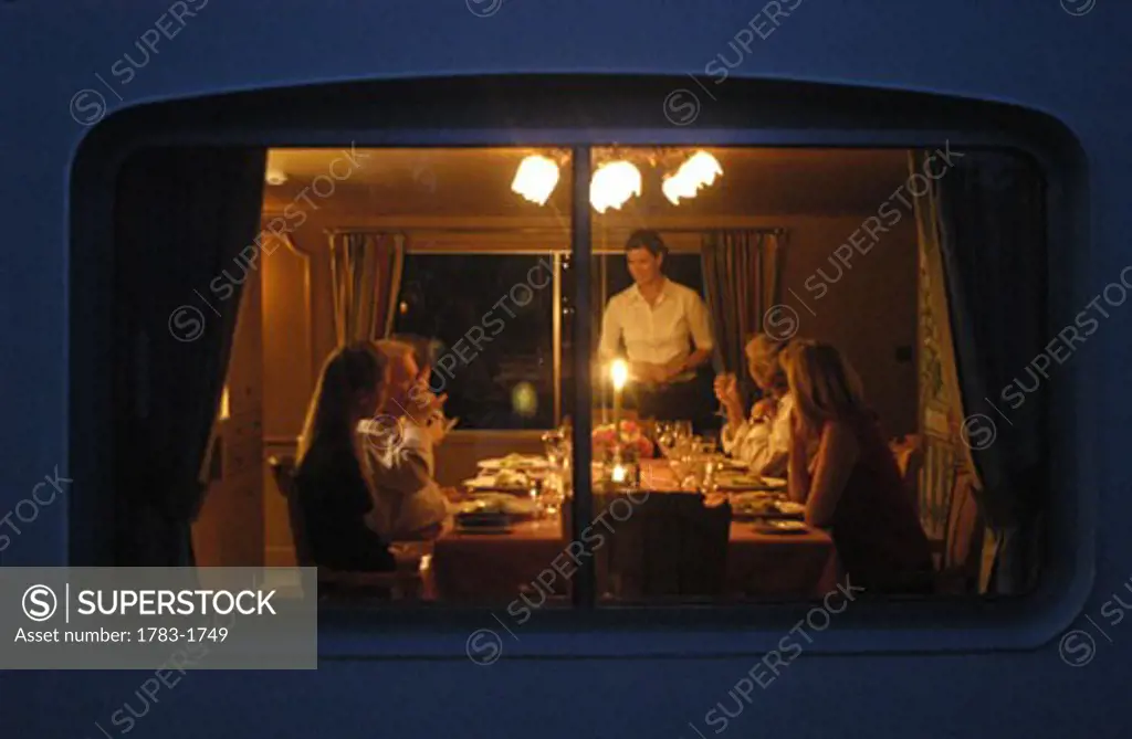 People in the dining room of  the Amaryllis, a French 'Peniche', moored in the evening on the Canal du Centre near Rully, Burgundy, France