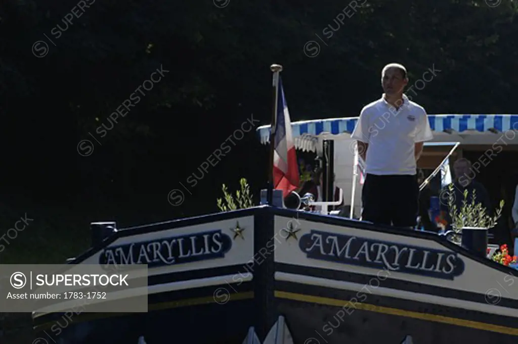 Crew member on the bow of The Amaryllis, a French 'Peniche', on the Canal du Centre near Chagny, Burgundy, France.