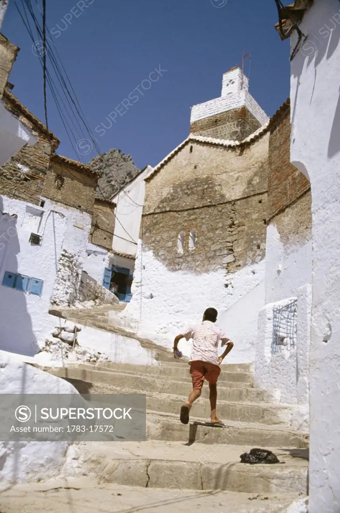 Boy climbing stone steps, Chaouen, Morocco