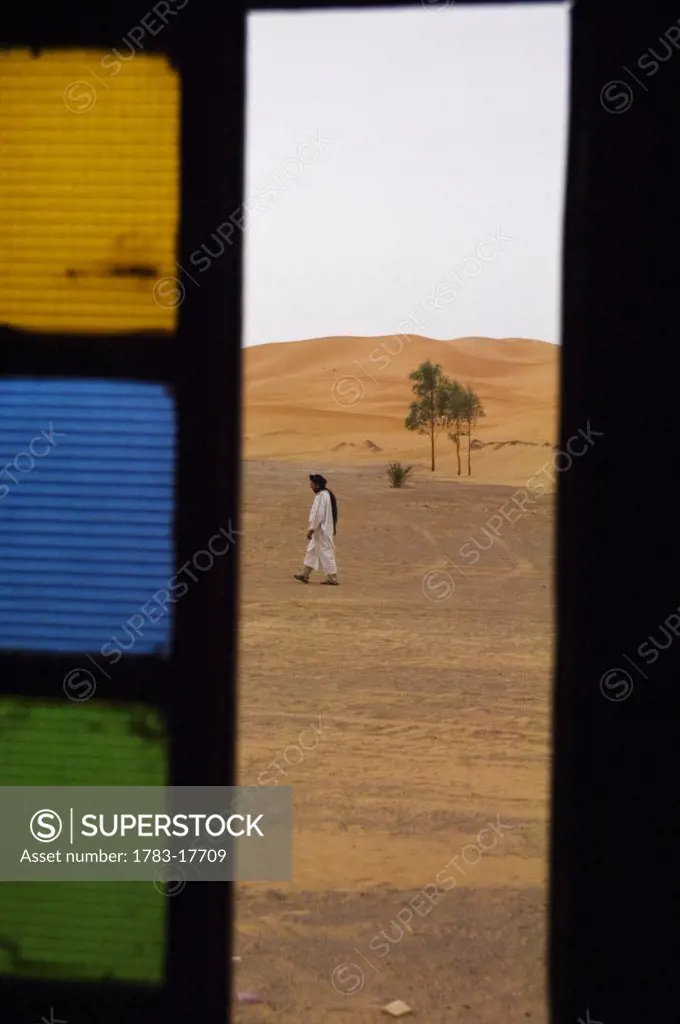 Berber man walking on desert, Erg Chebbi, Sahara Desert, Merzouga, Morocco.