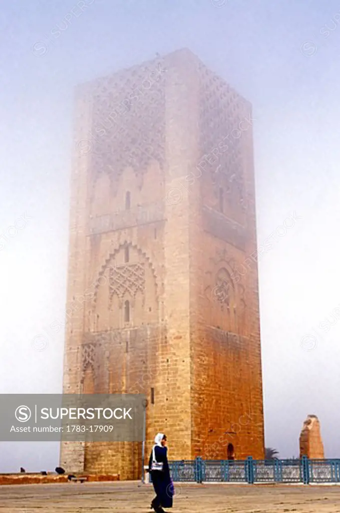 Woman walking in front of Hassan Mosque, Rabat, Morocco