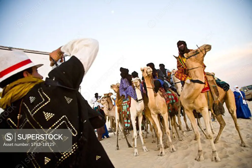 Tourist taking photos of Tuaregs on camels, Festival au Desert, Essakane, Mali.