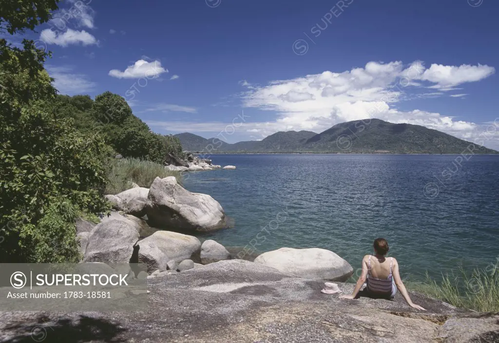 Woman sunbathing large rocks on the island of Domwe, Lake Malawi, Malawi