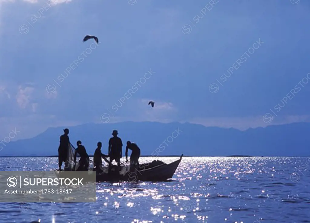 Fishermen pulling fishing nets on small boat on lake Chilwa, Malawi.