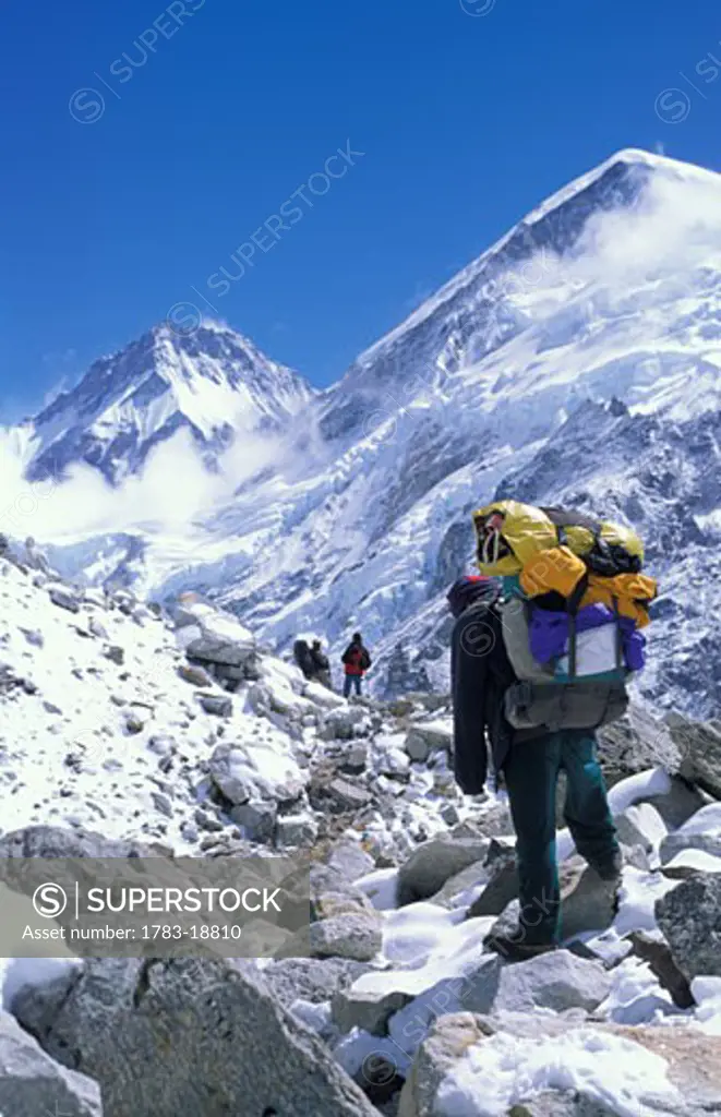 Trekkers and porter on trail to Gorak Shep, Everest west shoulder (R), Sagarmatha National Park, Solu Khumbu, Nepal
