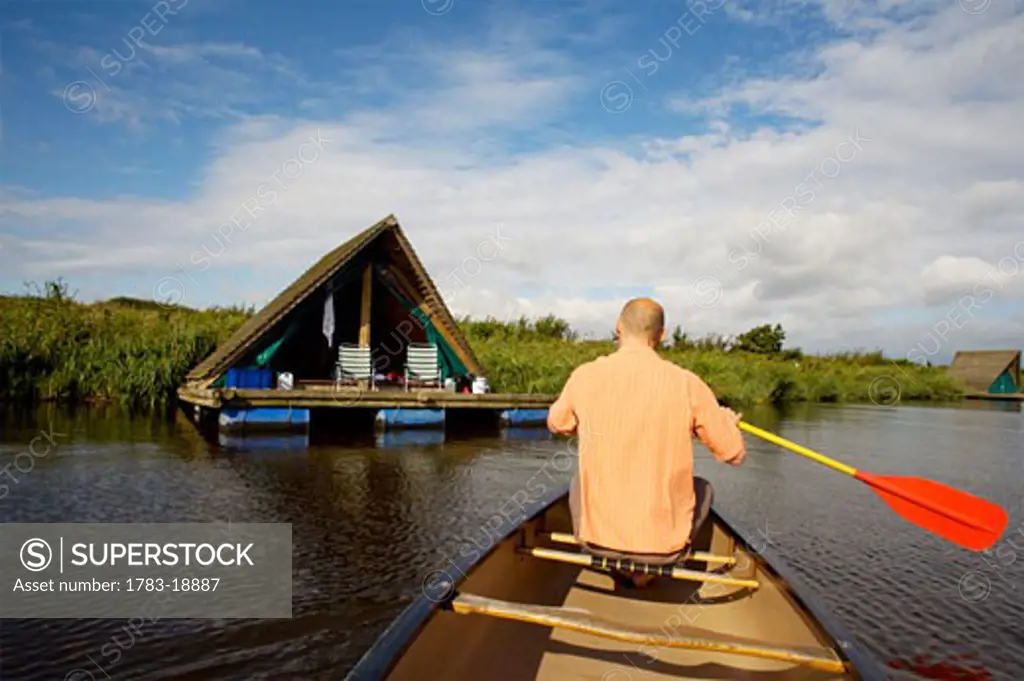 Man in boat and Camping Raft in background, DeHeen, Holland.