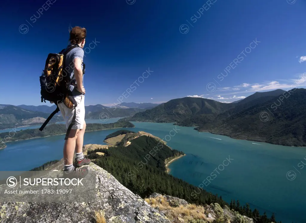 Woman standing on top of boulder and enjoying the view, South Island, New Zealand