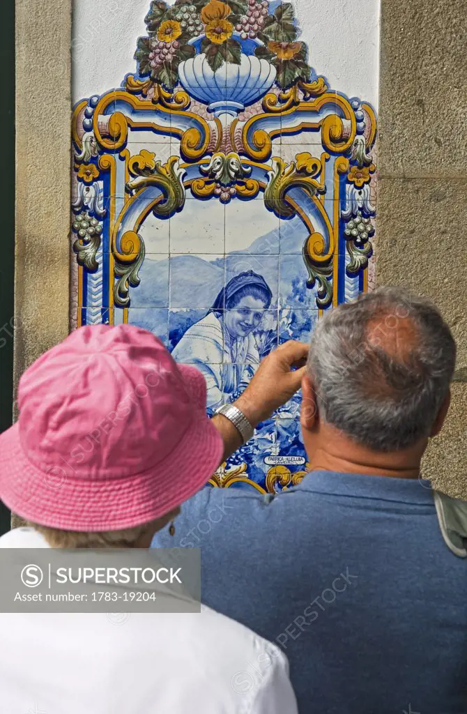 Couple photographing a  Quinta panel at the railway station at Pinhao, Douro Valley. Portugal