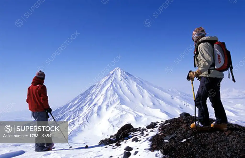 Two skiers admiring snowy peak, Kamchatka Peninsula, Russia