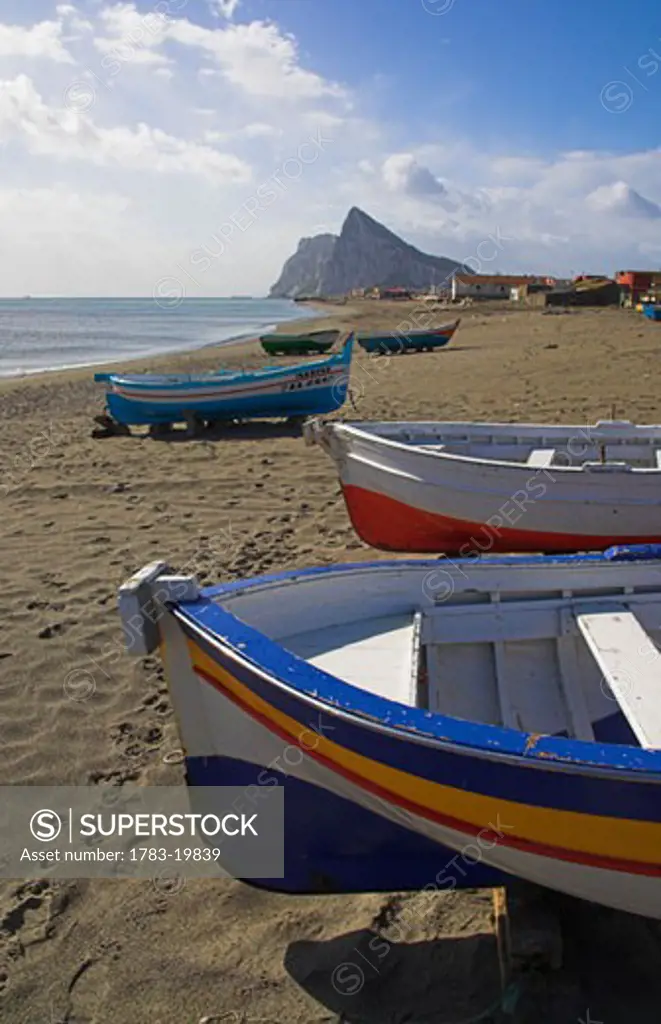 Painted fishing boats on beach and Rock of Gibraltar, La Linea, Costa del Sol, Spain