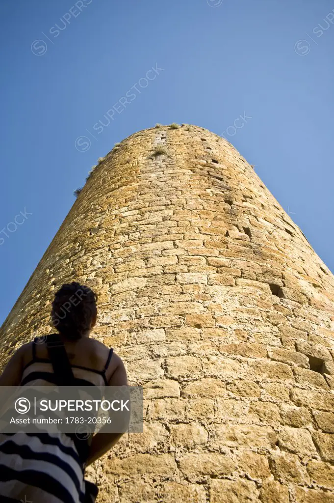 Girl looking at castle tower in medieval village, Pals, Costa Brava, Catalunya, Spain.