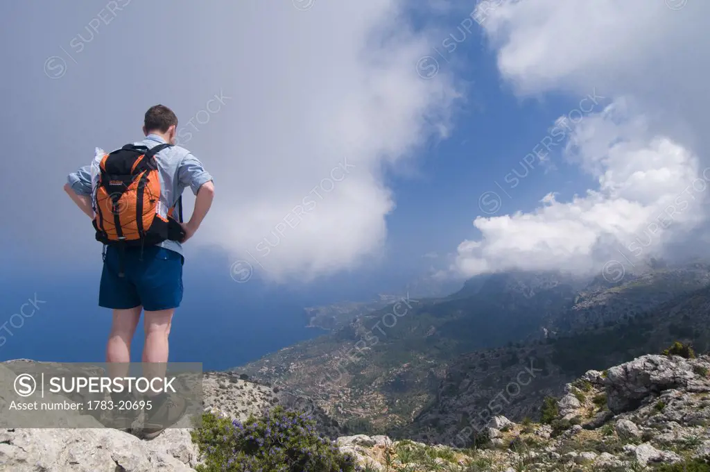 Hiker standing on edge of mountain looking at view, rear view, near Teix peak, Majorka, Ballearic Islands, Spain.