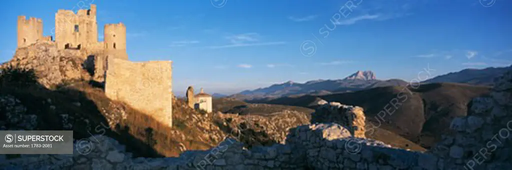 Looking out from ruins to the castle of Rocca Calascio at dawn and the peak of Corno Grande in the Campo Imperatore, Gran Sasso National Park, Abruzzo, Italy. 