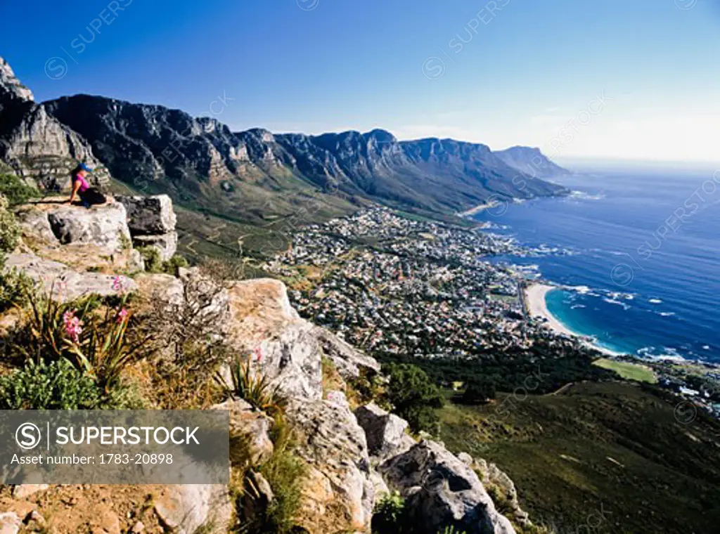 Hiker looking at Camps bay, sitting on top of hill, side view, Capetown, South Africa.