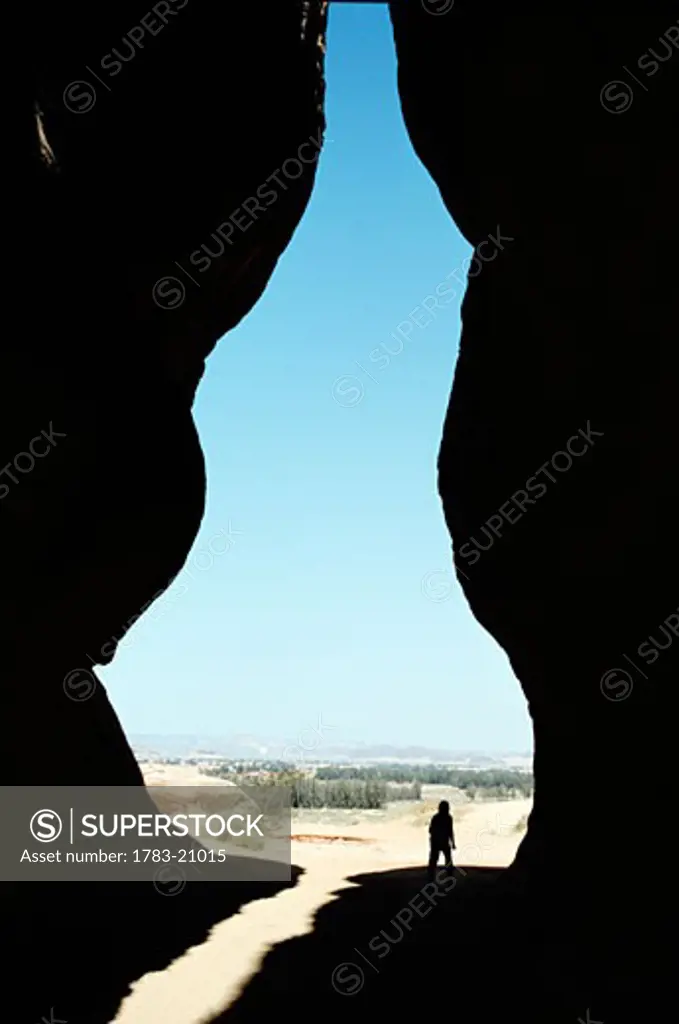Tourist standing in between eroded rocks at the Diwan, Madain Saleh, Saudi Arabia
