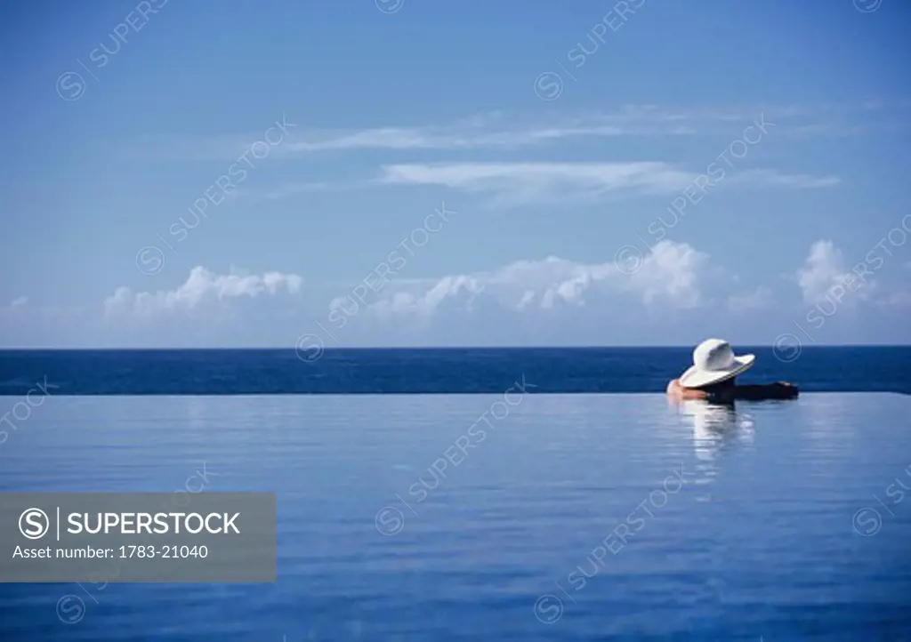 Woman wading in an infinity pool, Seychelles