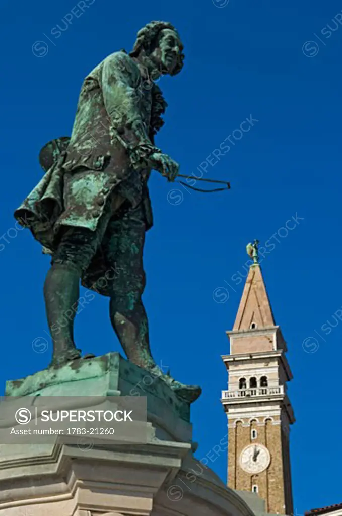 Statue of the local composer and violinist Giuseppe Tartini (1692-1770) and the clock tower of St. George's Cathedral., Piran, Slovenia.