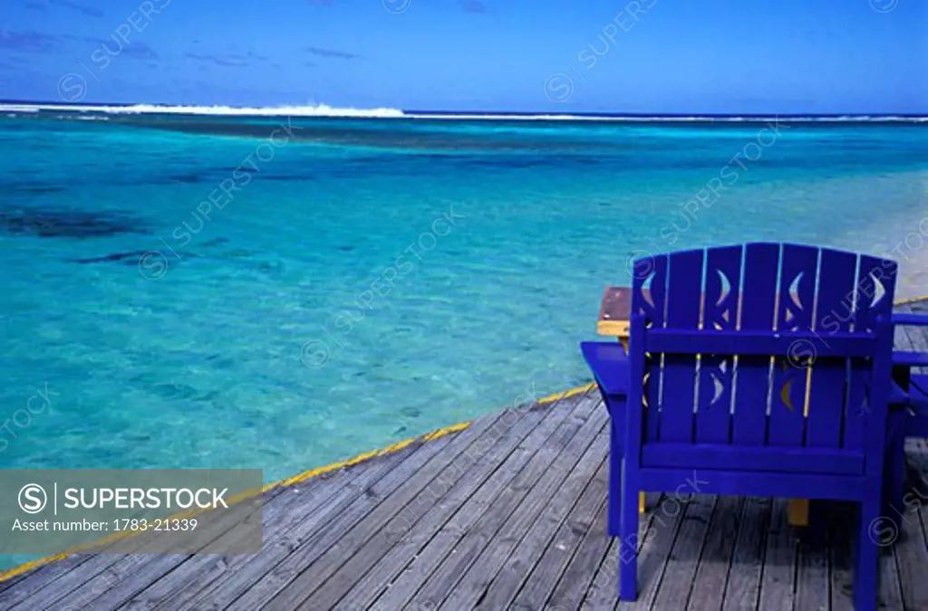 Empty blue painted chair on wooden deck by ocean, Aroa Beach, Rarotonga, Cook Islands