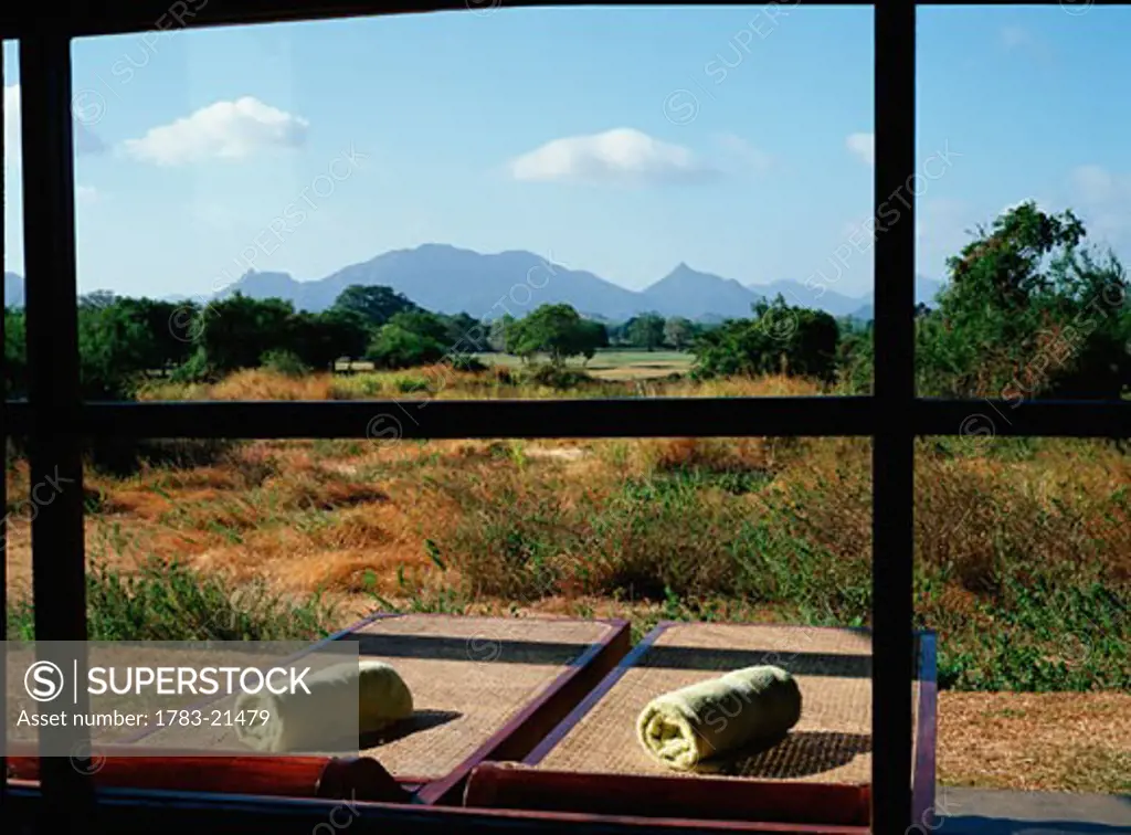 Two sunloungers and rural landscape as seen from a window, Sigiriya, Sri Lanka