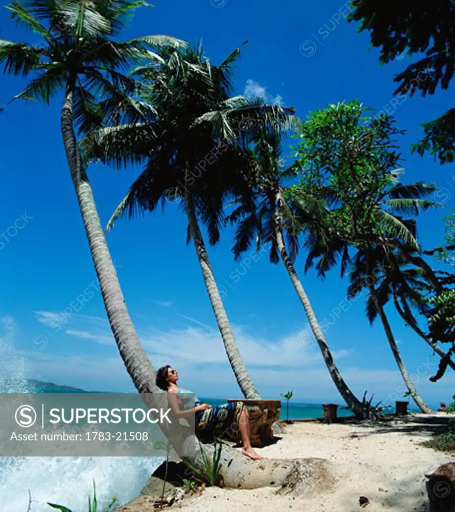 Sunbathing under palm trees with waves crashing on the shore, Taproban Island, Welligama Bay, Sri Lanka