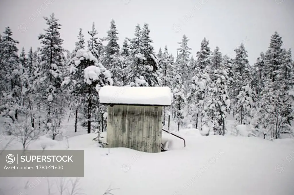 Snow covered cabin by forest, Abisko, Sweden.