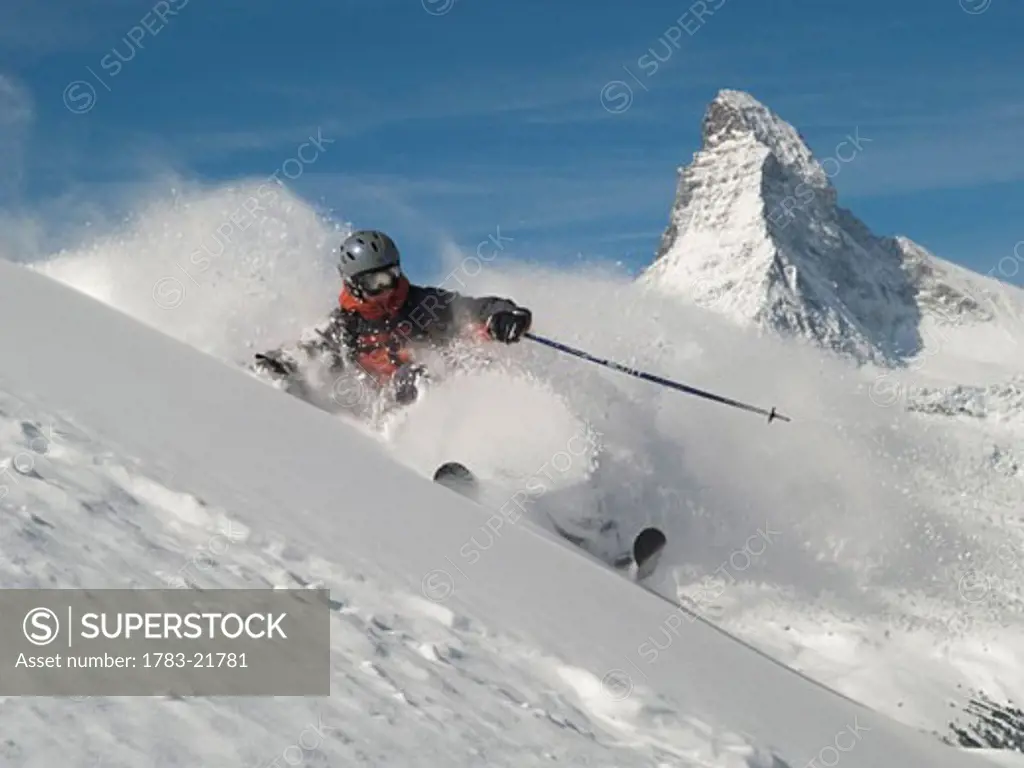 Helmeted free-rider skiing off piste with Matterhorn in the background, Hohtalli area, Zermatt, Switzerland. 
