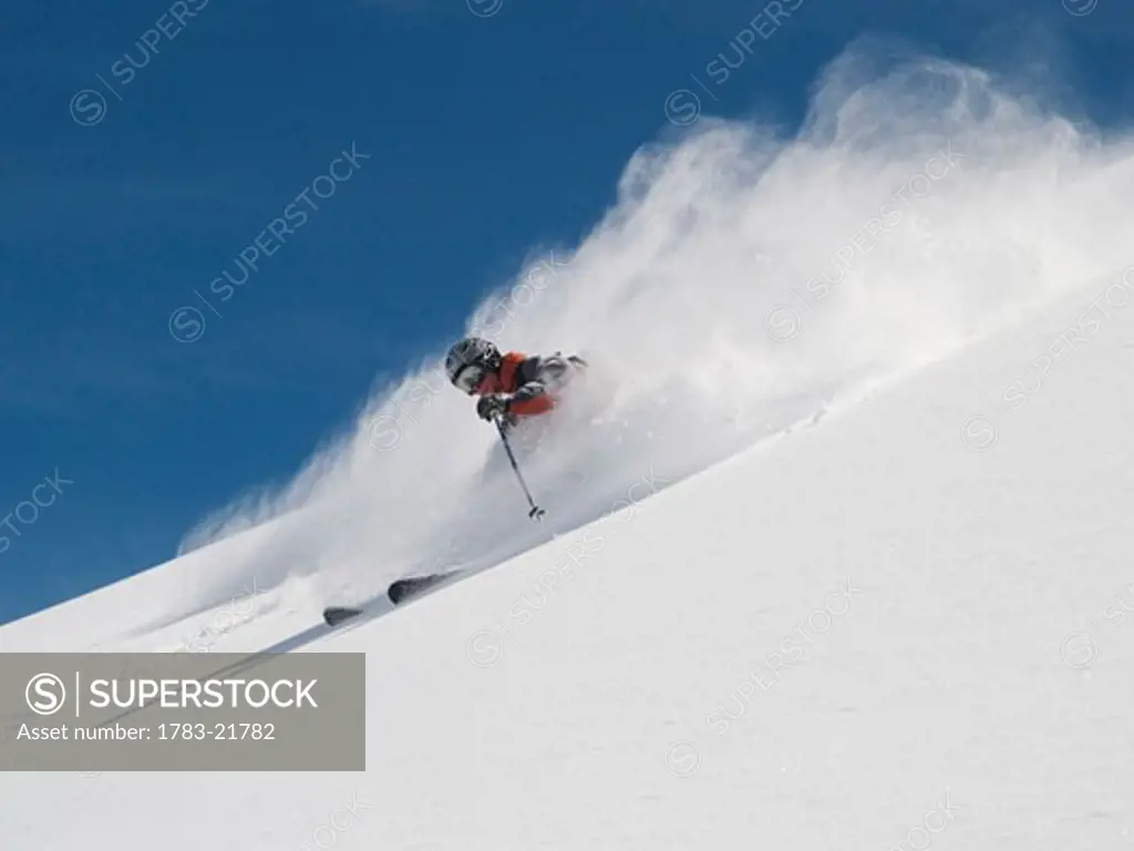 Helmeted free-rider with goggles skis off piste through fresh powder , Hohtalli area, Zermatt, Switzerland