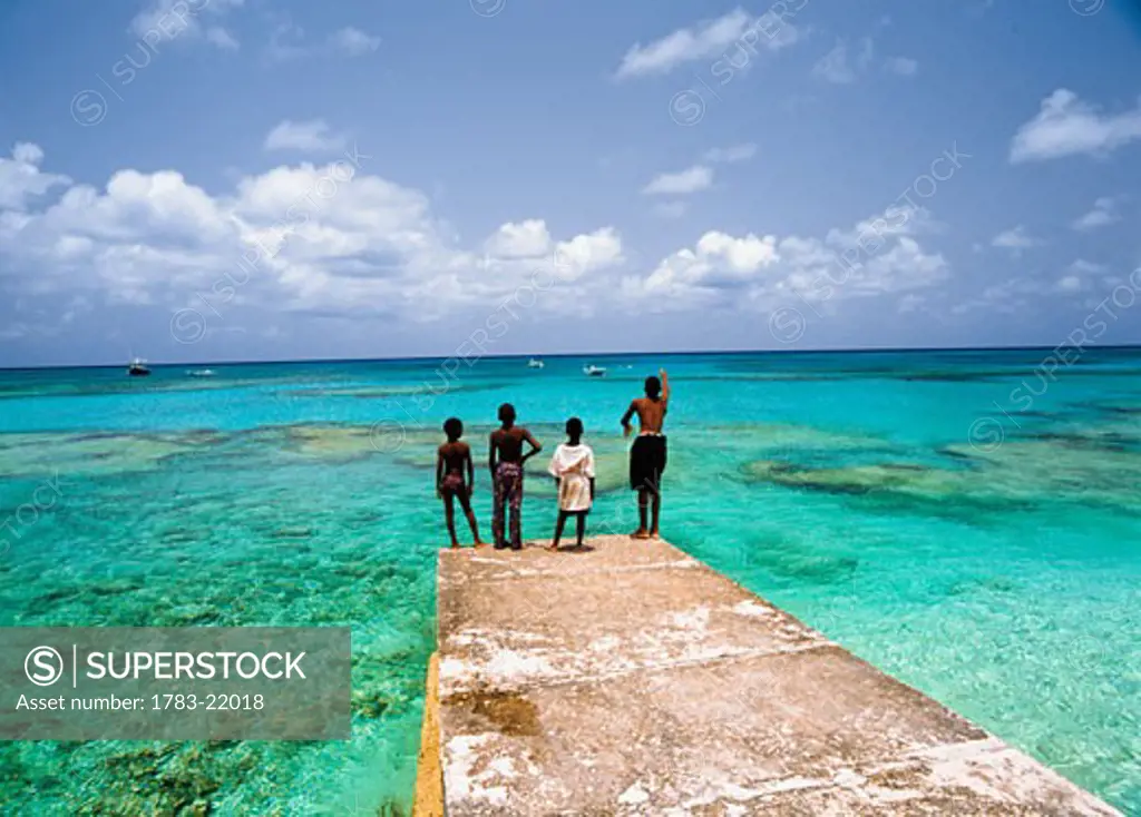 Four boys fishing off pier at ocean, Cockburn Town, Grand Turk, Turks and Caicos Islands.