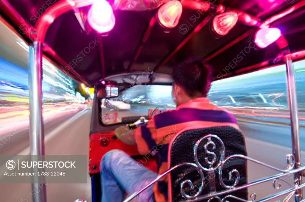 Man driving tuk-tuk at night, Bangkok, Thailand..