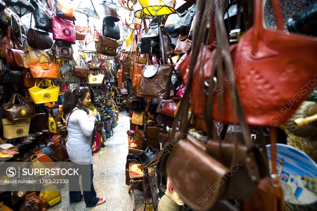 Female tourist buying a leather bag in souq, Tunis, Tunisia
