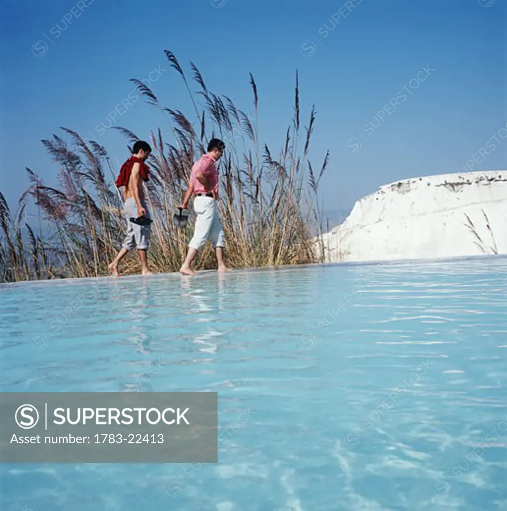 Couple walk beside the water, Travertine pools  , Pamukkale, Turkey.
